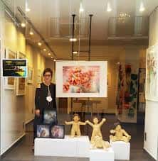 Interior de la galería con exposición de esculturas y obras enmarcadas, incluyendo una figura humana central