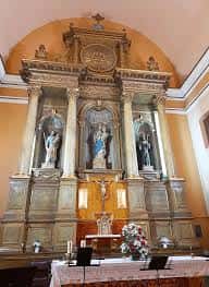 Altar mayor con retablo barroco y estatuas religiosas en el interior de la iglesia