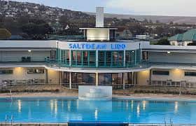 Fachada del Saltdean Lido al atardecer con luces encendidas