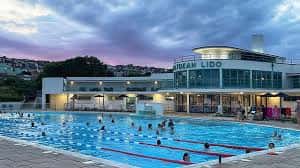Piscina del Saltdean Lido con bañistas y cielo crepuscular