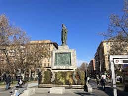 Monumento central en la plaza con estatua y base decorativa bajo cielo despejado