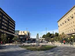 Plaza abierta con fuente, árboles y edificios modernos en un día soleado