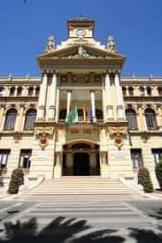 Entrada monumental del Ayuntamiento de Málaga con escalinata y sombra de palmeras