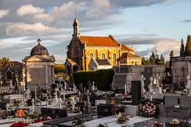 Iglesia del cementerio al atardecer con tumbas y monumentos en primer plano