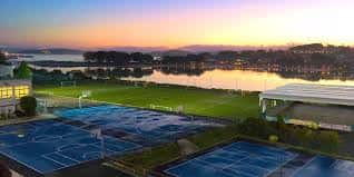 Pistas deportivas del colegio al atardecer con vista al mar y cielo anaranjado