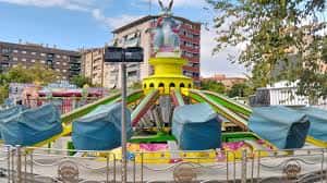 Carrusel colorido en el recinto ferial de Las Fuentes con edificios residenciales al fondo