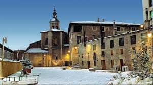Plaza del Machete cubierta de nieve con la torre de la iglesia iluminada, escena invernal única