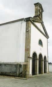 Vista exterior de la Iglesia Parroquial del Divino Salvador en Serantes, con fachada blanca y campanario de piedra