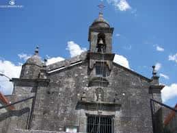 Detalle del campanario y fachada de la iglesia del Divino Salvador bajo cielo azul