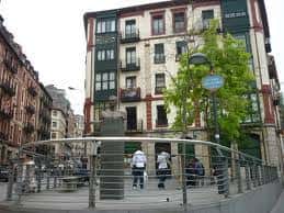 Vista general de la Plaza Doctor Fleming con el busto de Alexander Fleming en primer plano y edificios tradicionales al fondo