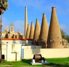 Vista del patio con chimeneas industriales y elementos patrimoniales como cañón y palmeras