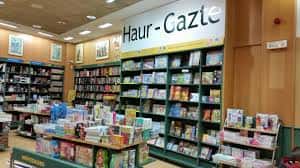 Interior de la librería con estanterías llenas de libros y señalización en euskera