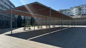 Estructura de sombra con mesas y bancos en la plaza, ideal para eventos al aire libre