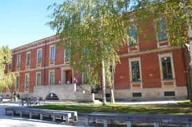 Vista exterior del Pabellón Universitario del Campus de Álava con fachada de ladrillo y árboles en primer plano