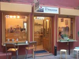 Vista frontal del restaurante Il Boccone con entrada abierta y mobiliario exterior