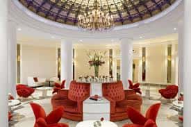 Lobby principal del hotel con cúpula decorada y mobiliario elegante en tonos rojos