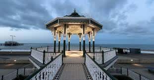 Brighton Bandstand al atardecer con iluminación interior y vista al mar en el fondo