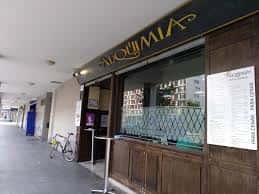 Fachada exterior de la cafetería Alquimia en Vitoria-Gasteiz, con letrero dorado y menú colgado
