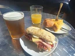 Desayuno al aire libre con bocadillo, cerveza, zumo y tortilla en mesa metálica