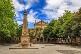 Plaza de Recoletas en un día soleado con el obelisco rodeado de árboles frondosos