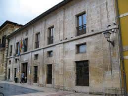 Vista lateral del edificio del Centro Social Campomanes con banderas y farola