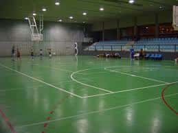 Cancha de baloncesto en uso dentro del pabellón con espectadores en las gradas