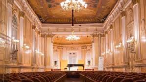 Interior de la Sala Fundación Unicaja María Cristina con butacas rojas y piano en el escenario