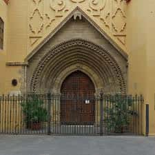 Portada principal gótica de la iglesia con puerta de madera y reja