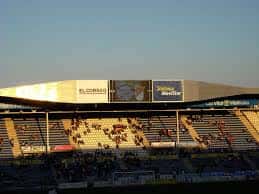 Vista exterior del estadio al atardecer con publicidad en la fachada