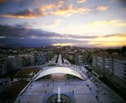Vista aérea de la plaza La Losa al atardecer con el puente peatonal y la fuente central