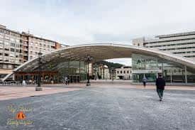 Fachada moderna de la estación de tren en la plaza La Losa con estructura arqueada de cristal
