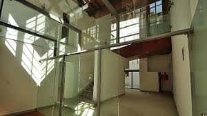 Interior moderno del Ateneo Ferrolán con escalera de cristal y espacios diáfanos aptos para eventos
