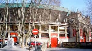 Fachada exterior de la Plaza de Toros de Pamplona con árboles y señalización