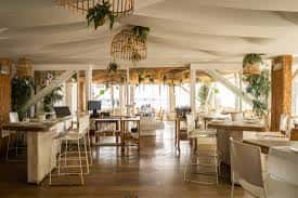 Interior del restaurante con decoración natural, mesas dispuestas y iluminación cálida