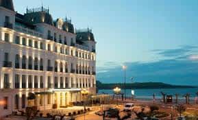 Fachada iluminada del hotel al atardecer con vista al mar y ambiente cálido