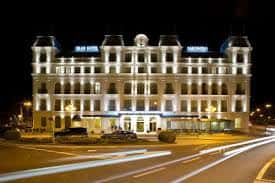 Hotel iluminado por la noche con luces de tráfico en movimiento, destacando su presencia urbana y lujosa