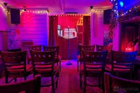 Interior del club con iluminación de colores y sillas dispuestas para el público