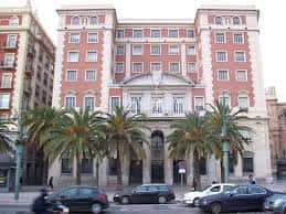 Fachada principal de la Diputación Provincial de Málaga con palmeras y tráfico urbano