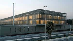 Fachada iluminada de la sede de la Diputación al atardecer, destacando su arquitectura moderna