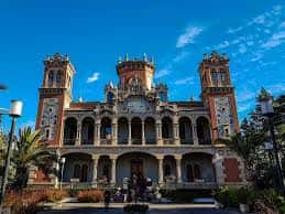 Vista frontal del palacio bajo cielo azul, mostrando su simetría y detalles ornamentales