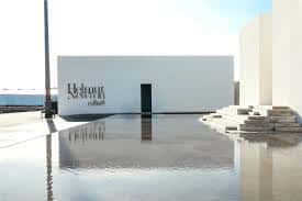 Fachada principal del Centro MOP con logotipo y piscina reflectante