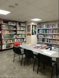 Interior de la Biblioteca Ecologista Gaia con estanterías llenas de libros y una mesa central para reuniones