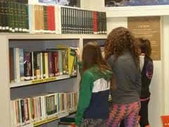 Visitantes explorando los libros en las estanterías de la biblioteca