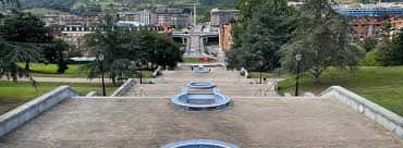 Perspectiva elevada de las fuentes y escalinatas del parque con fondo urbano