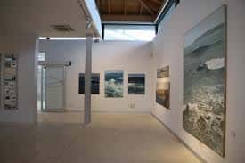 Interior de sala de exposiciones con obras de arte marinas y techumbre de madera