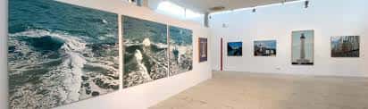 Galería principal con grandes paneles fotográficos del océano y vistas del faro