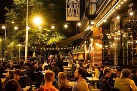 Terraza exterior del pub por la noche con luces cálidas y ambiente festivo