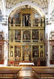 Interior de la iglesia con retablo principal y bancos de madera