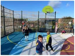 Niños jugando en una cancha de baloncesto cubierta en el parque