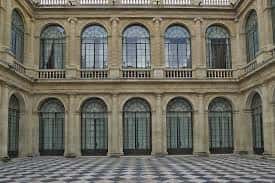 Patio interior del edificio con arcos de medio punto y suelo de baldosa geométrica